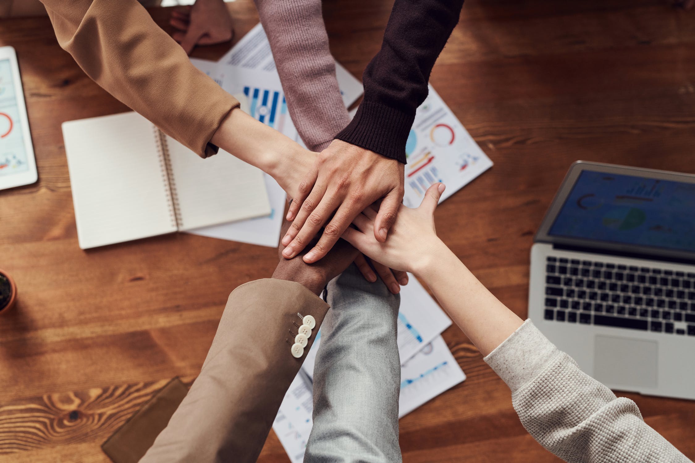 A group of people crossing hands together in a circle. 