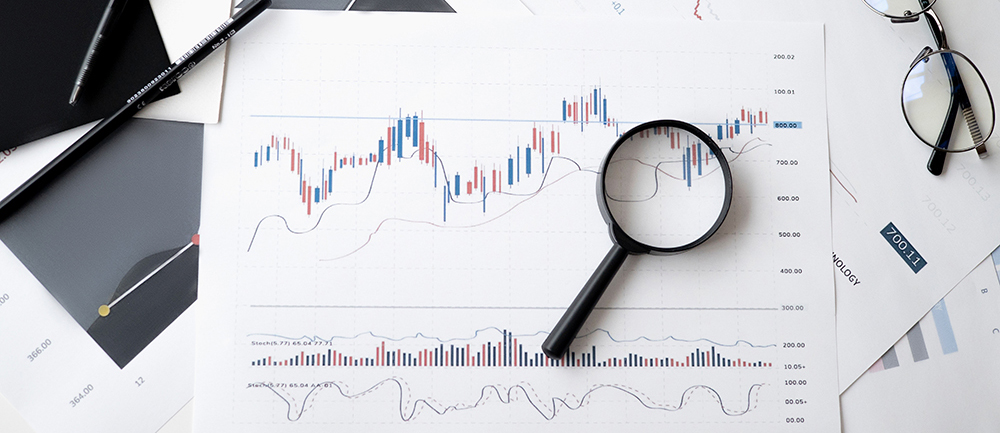 Stock image of charts and glasses and a magnifying glass