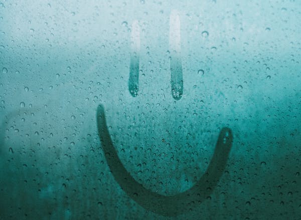 Smiley face drawn on steamed up window. Pexels image.