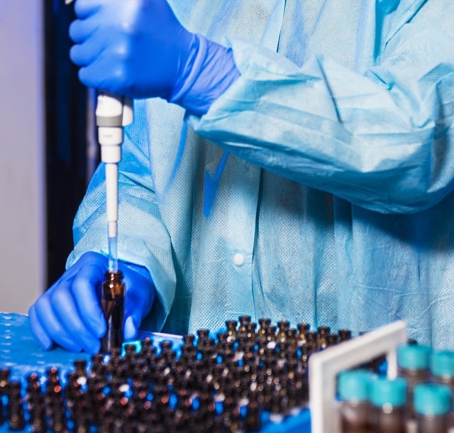 gloved hands squeezing liquid into vials